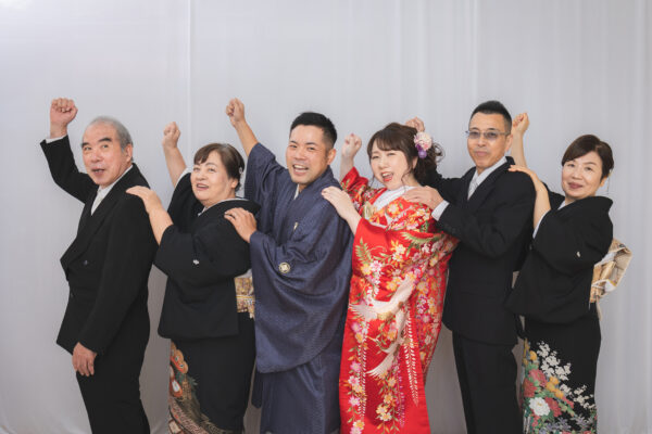 和装の二人を中心に大人6人が並ぶ集合写真