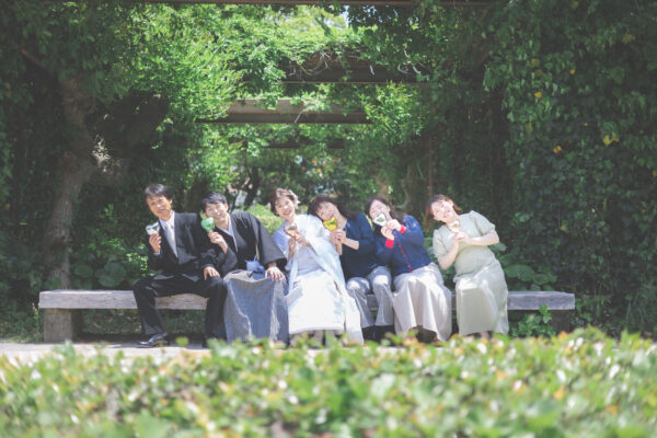 緑に囲まれた屋外ベンチでの6人の集合写真